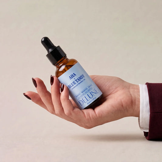 Delune AHA + Blue Tansy Overnight Renewal Oil held in an open hand