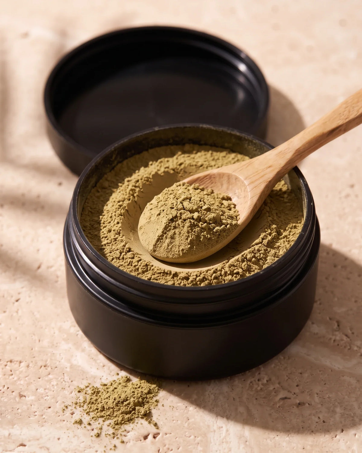 Open jar of Delune Nontronite Glacial Clay showing the soft dry olive clay powder with a wooden spoon