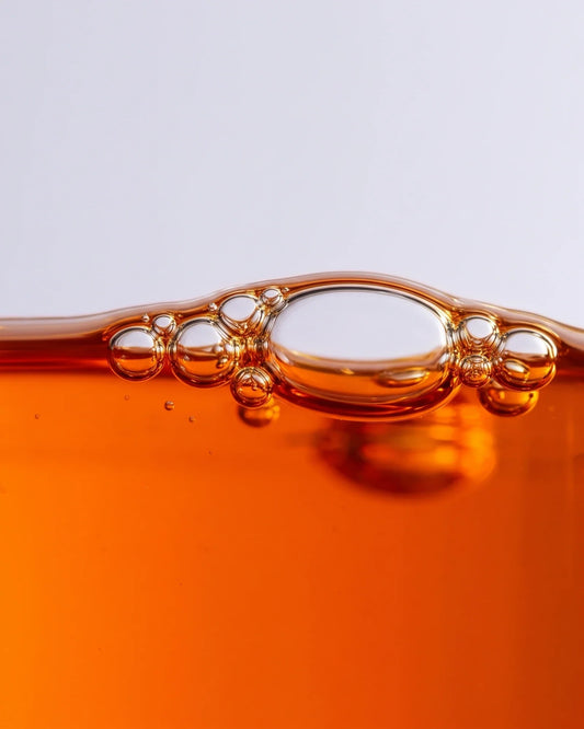 Revive 49% Sea Buckthorn Oil Serum texture: macro of vivid orange sea buckthorn oil with bubbles at the surface