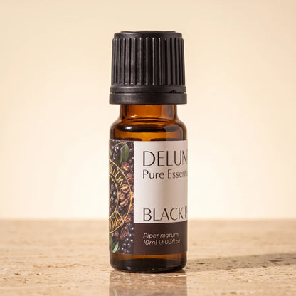 Delune Black Pepper Pure Essential Oil, 10ml amber glass bottle on warm travertine stone