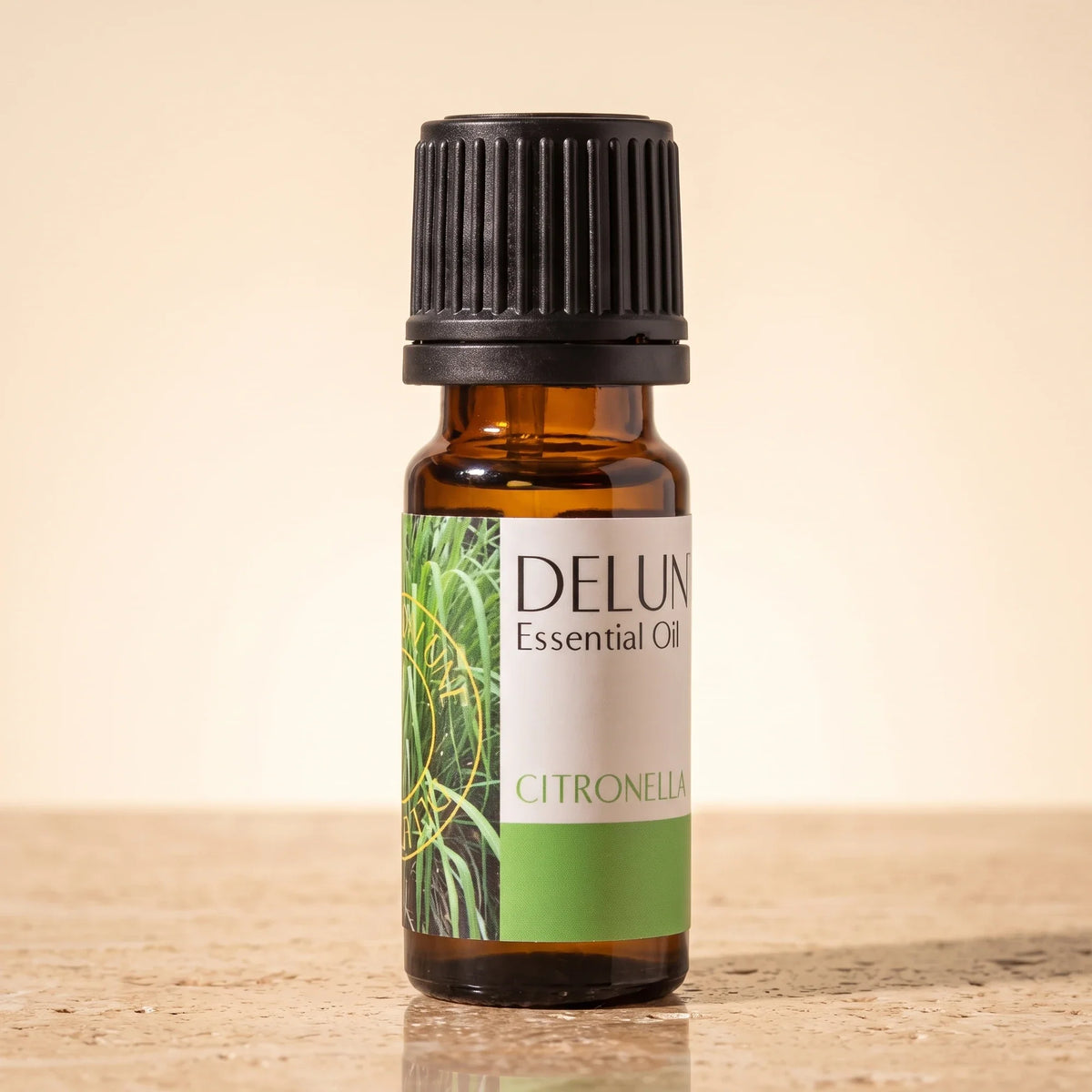 Delune Citronella Pure Essential Oil, 10ml amber glass bottle on warm travertine stone