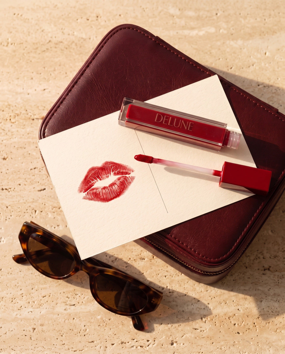 Delune LuxMatte in Jet-Set Red with a red kiss on a postcard